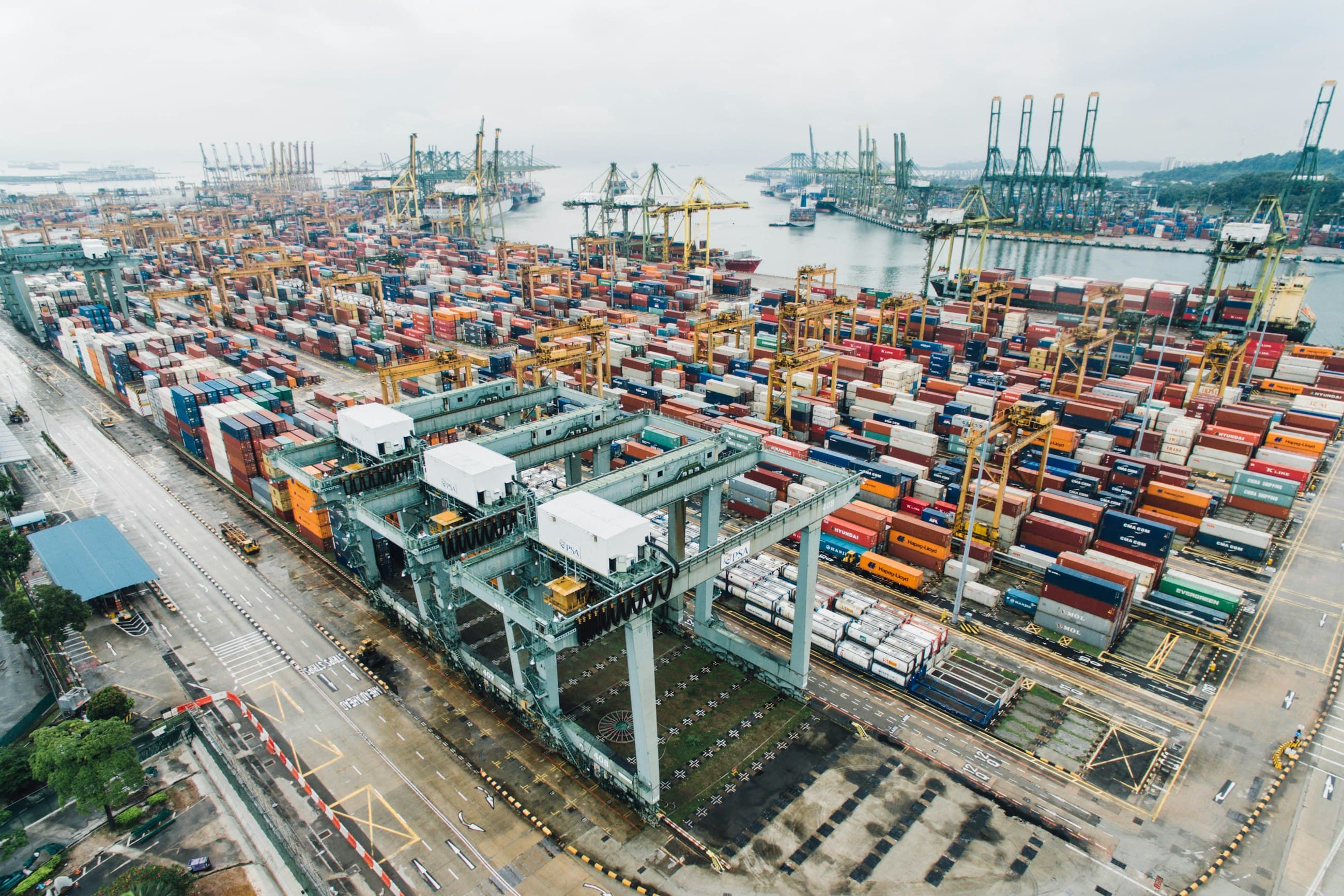 Aerial view of a busy container port with stacked shipping containers and cranes