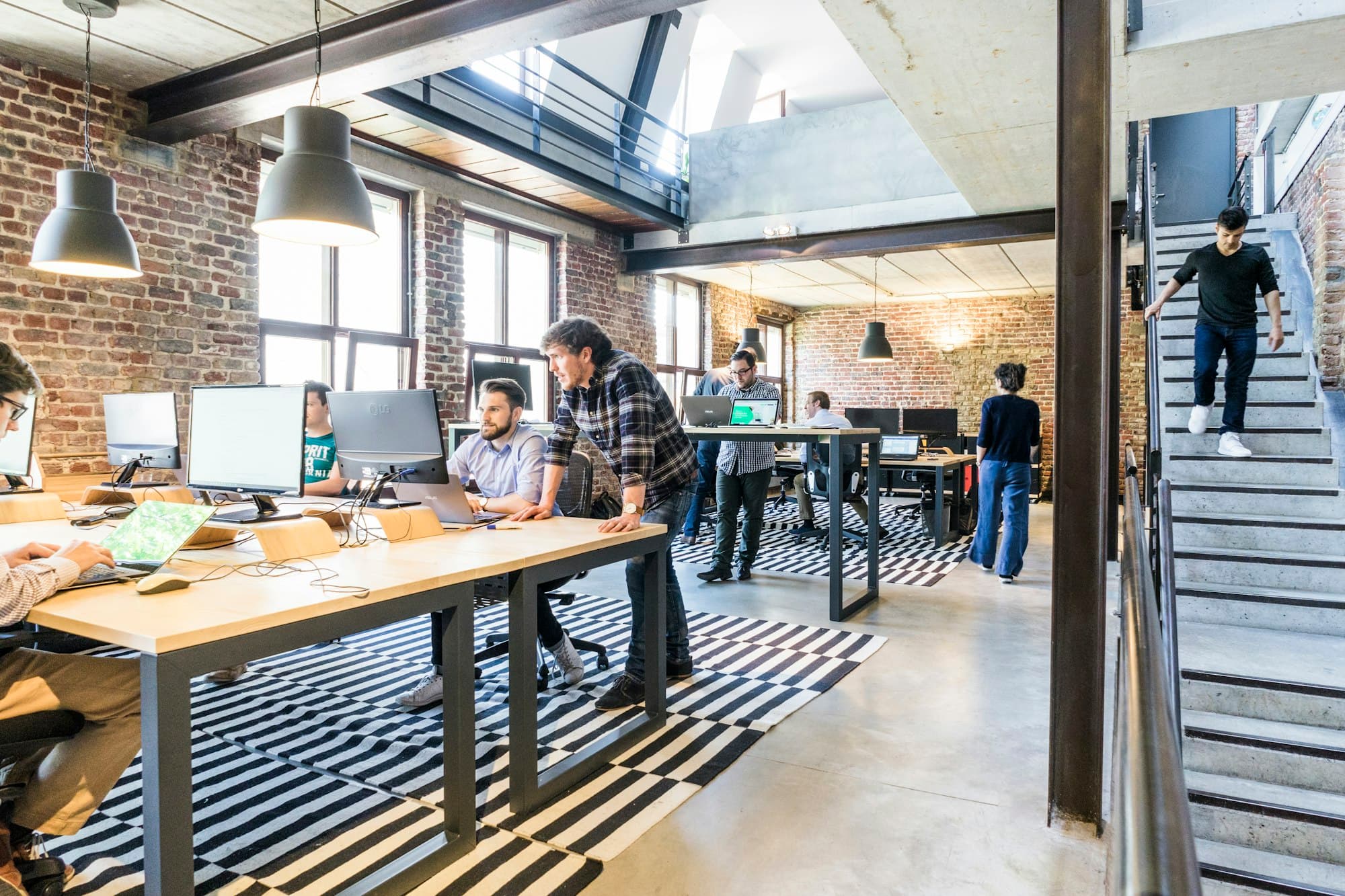 An open studio office with brick walls, pendant lights and people at work
