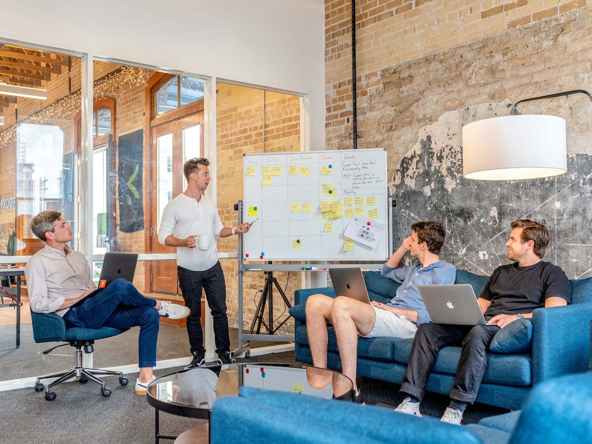 A facilitator at a whiteboard leading a small team working session in a converted warehouse office